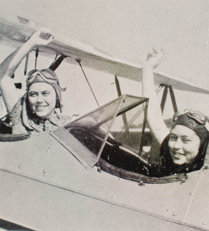 Women-students wave from an airplane