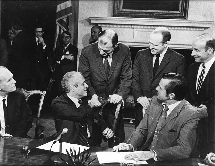 A group of men shake hands as the University is officially signed as a public instutition