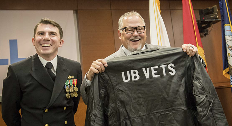 Bob Parsons holds a jacket that reads UB Vets during a celebration for a new veterans center named after him.