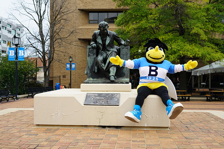 Eubie, the bee mascot, sits on the base at the Edgar Allan Poe statue.