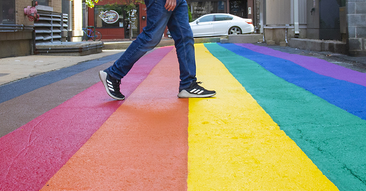 Someone walks across a repainted alley, now called Inclusion Alley, which features the Philadelphia Pride Flag.