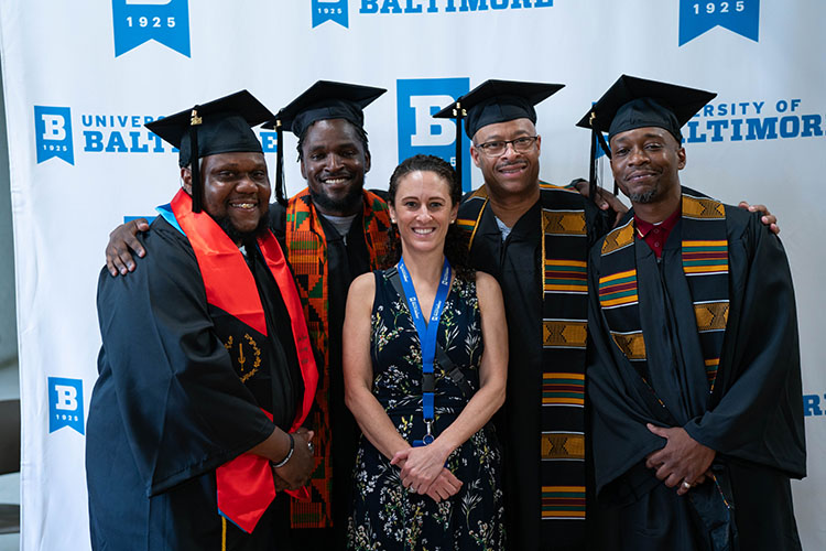 Students of the Second Chance program pose with program director and professor Andrea Cantora during their commencement ceremony in 2024.