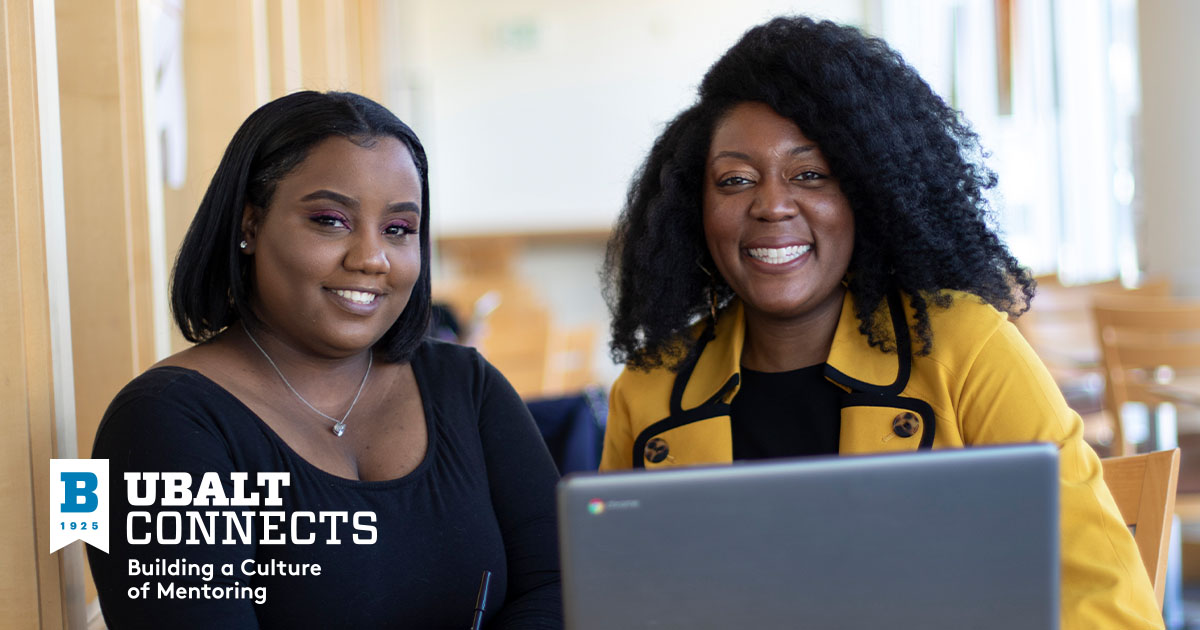 Mentor and mentee smiling in front of laptop 