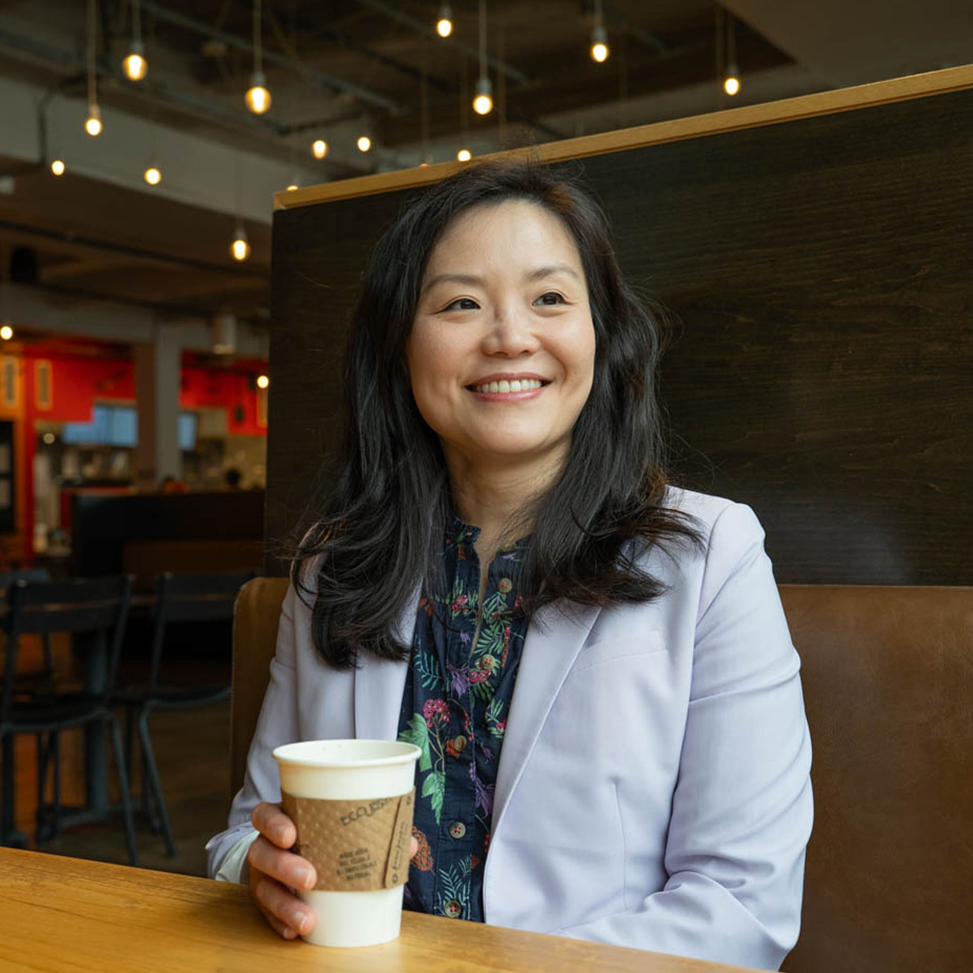 Rae Tan poses with a cup of coffee in a booth at R. House.