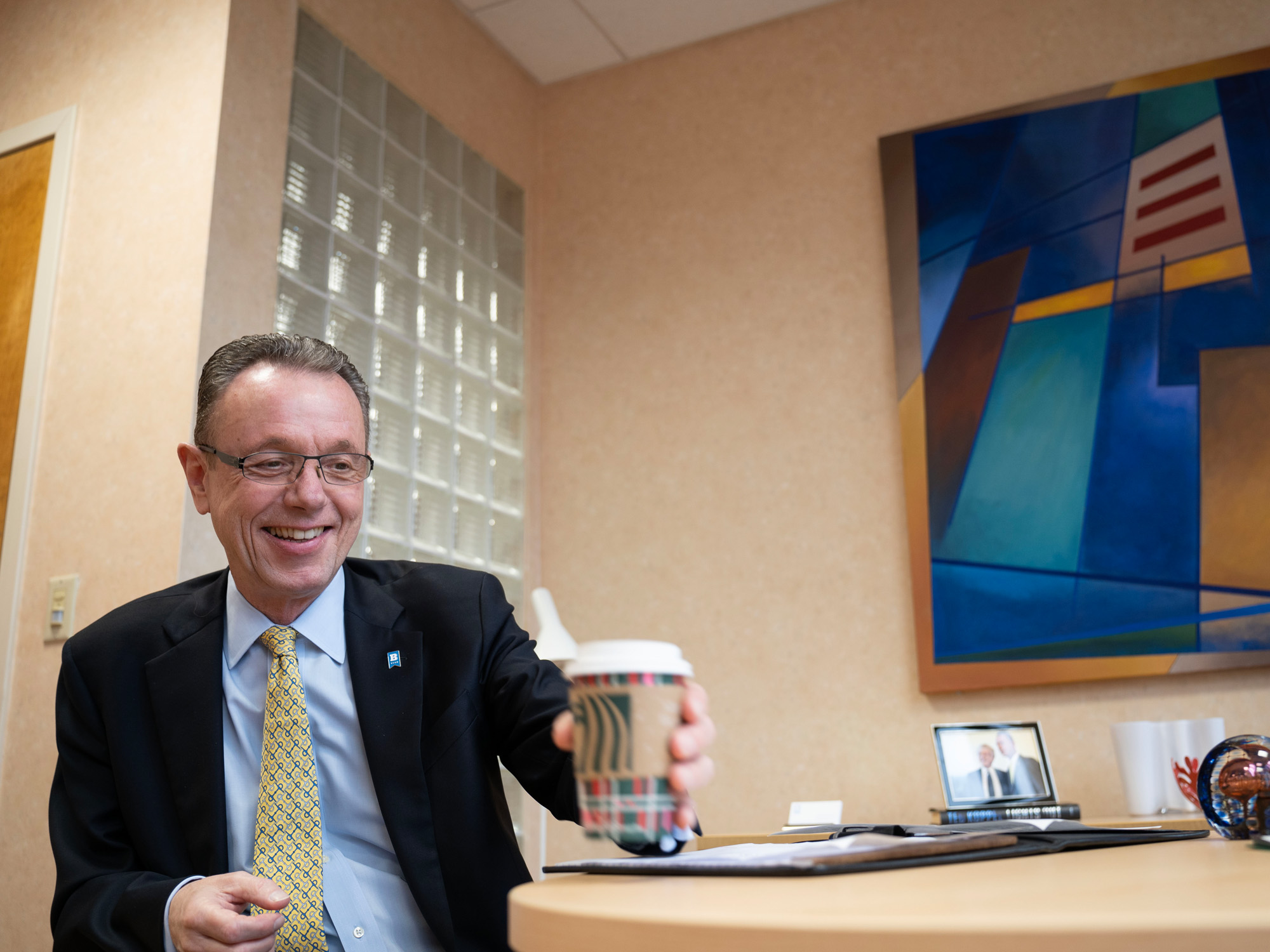 Ralph Mueller reaches for his coffee cup during an interview in his office. 