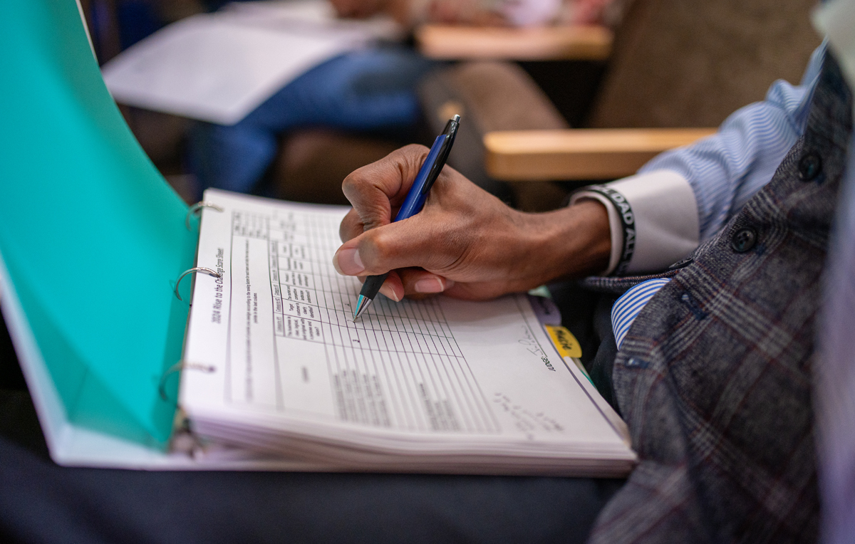 a man writing in a notebook reviewing a business pitch